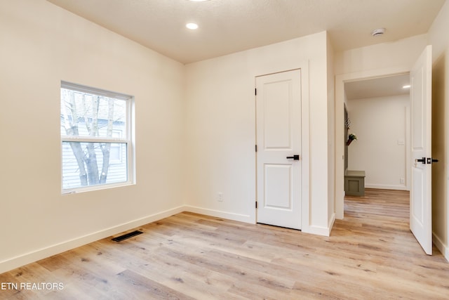 unfurnished room featuring recessed lighting, light wood-style floors, visible vents, and baseboards