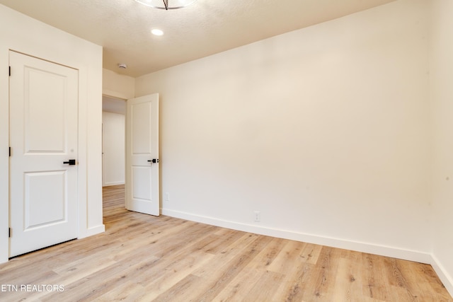 empty room featuring baseboards, a textured ceiling, and wood finished floors