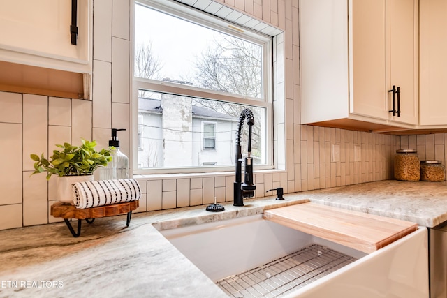 kitchen featuring a sink, tasteful backsplash, white cabinets, and light countertops