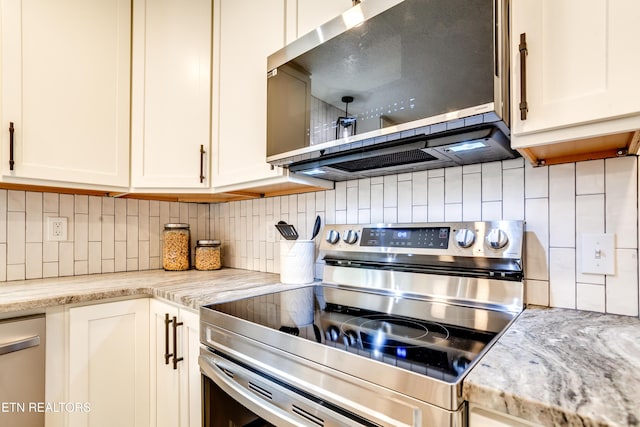 kitchen with tasteful backsplash, white cabinets, appliances with stainless steel finishes, and light stone countertops