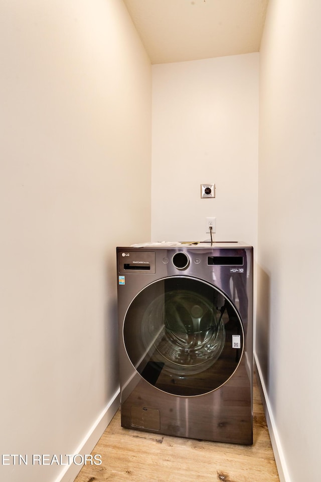 laundry area featuring laundry area, washer / dryer, baseboards, and wood finished floors