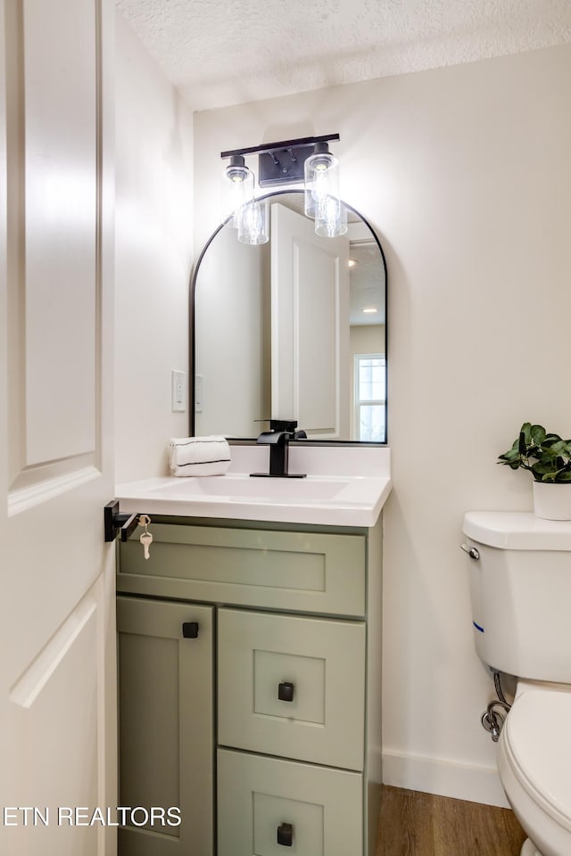 bathroom featuring vanity, wood finished floors, baseboards, a textured ceiling, and toilet