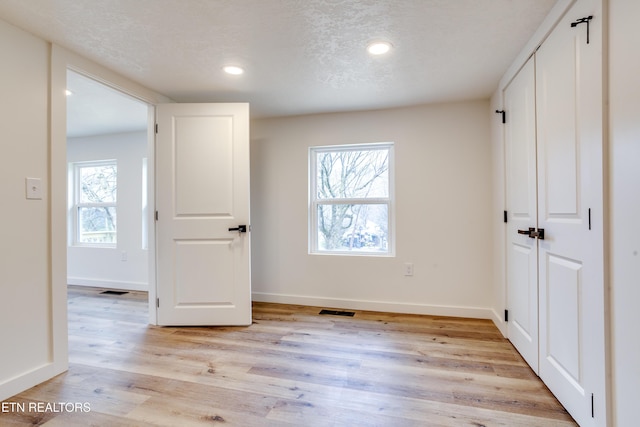 unfurnished bedroom with light wood finished floors, recessed lighting, a textured ceiling, and baseboards