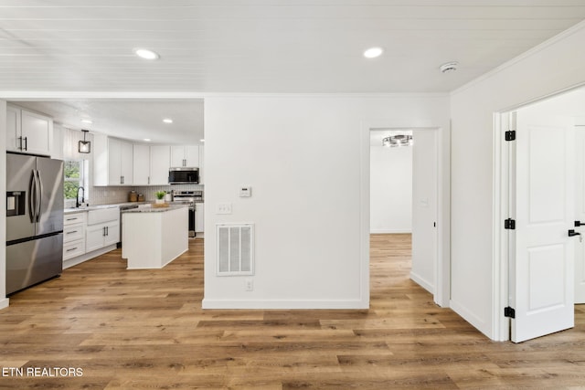 kitchen featuring ornamental molding, visible vents, stainless steel appliances, and light wood-style floors