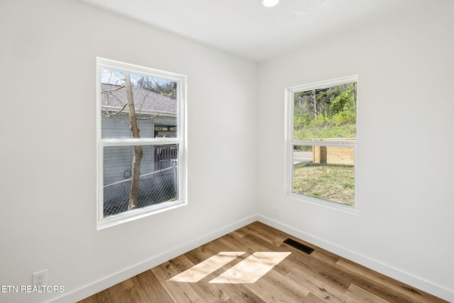 empty room with baseboards, visible vents, and wood finished floors