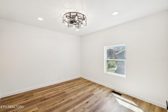 empty room featuring baseboards, visible vents, light wood-style flooring, and recessed lighting
