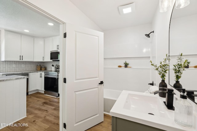 interior space with a bath, tasteful backsplash, walk in shower, and wood finished floors