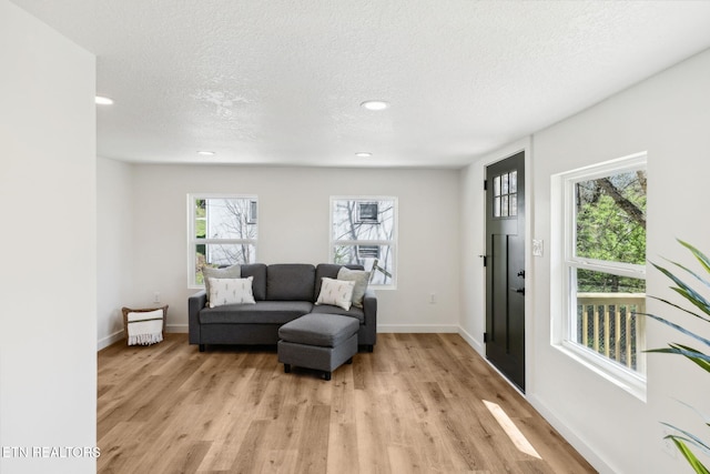 living area featuring baseboards, a textured ceiling, light wood-style flooring, and recessed lighting