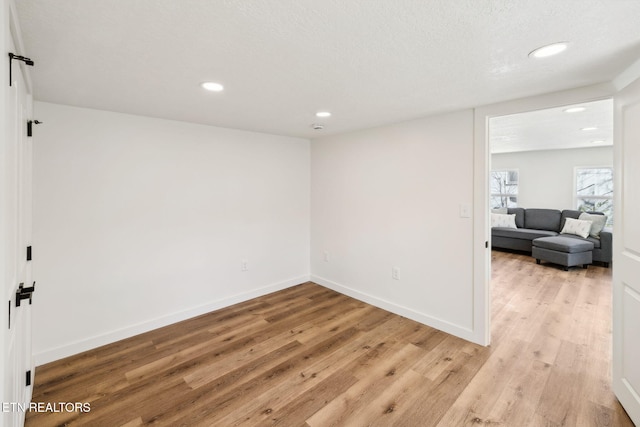 spare room featuring baseboards, light wood-style floors, and recessed lighting
