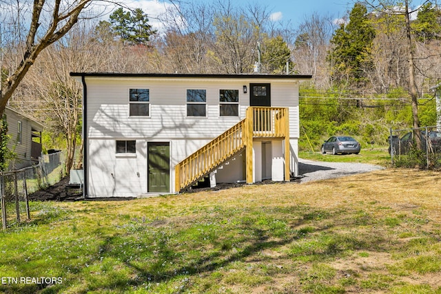 rear view of property featuring a lawn, stairs, and fence
