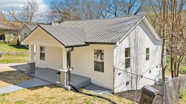view of property exterior with metal roof and fence