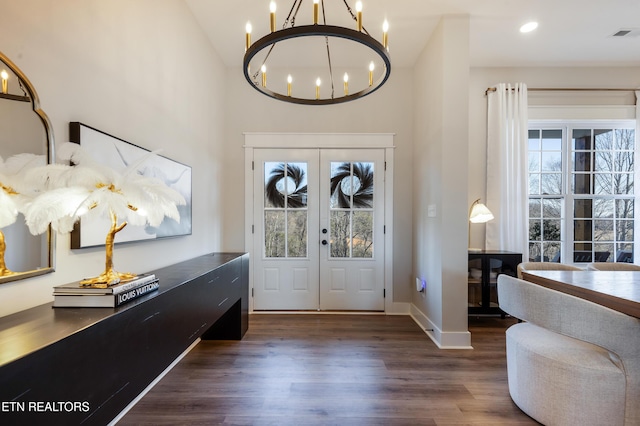 foyer entrance with a wealth of natural light, french doors, wood finished floors, and a chandelier