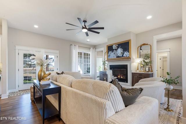 living room with a glass covered fireplace, recessed lighting, a ceiling fan, and wood finished floors