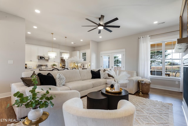 living room with recessed lighting, baseboards, wood finished floors, and ceiling fan with notable chandelier