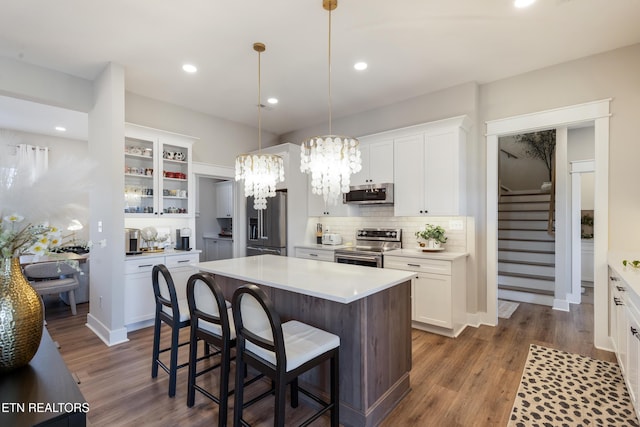 kitchen featuring a breakfast bar, a center island, stainless steel appliances, an inviting chandelier, and white cabinets