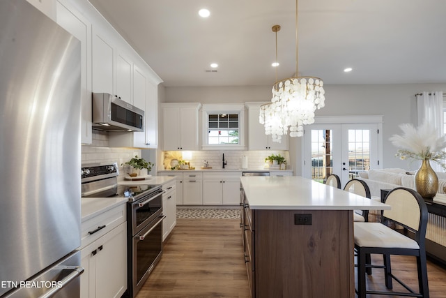 kitchen with a breakfast bar, tasteful backsplash, a center island, stainless steel appliances, and light countertops