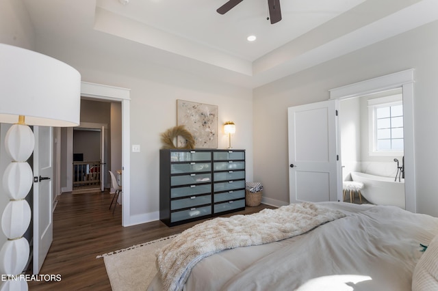 bedroom with dark wood finished floors, a tray ceiling, recessed lighting, and baseboards