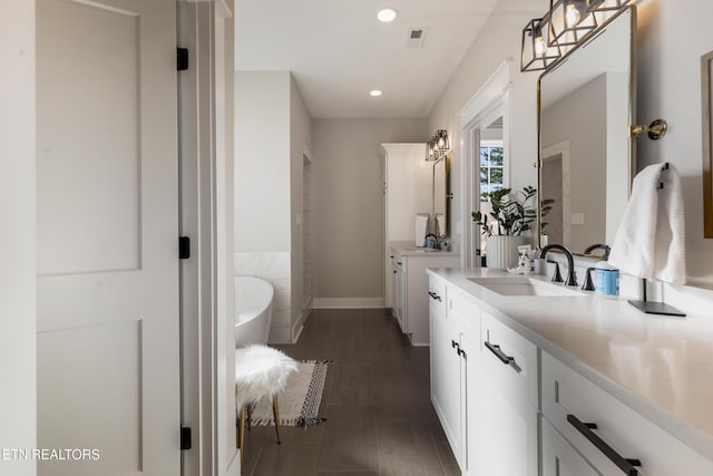 full bathroom with two vanities, a washtub, recessed lighting, and a sink