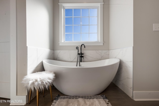 bathroom featuring a soaking tub, tile walls, and a wainscoted wall