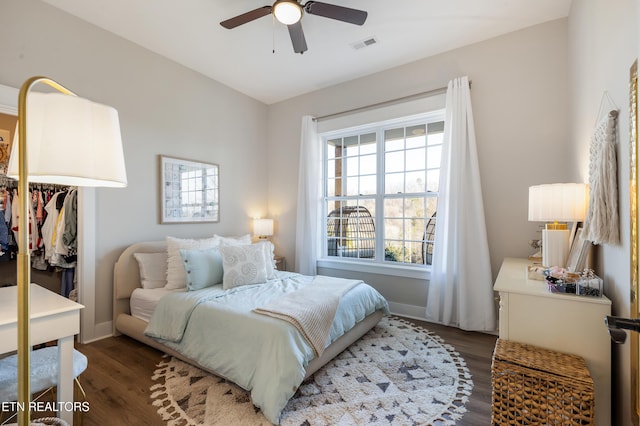 bedroom with a ceiling fan, wood finished floors, visible vents, and baseboards