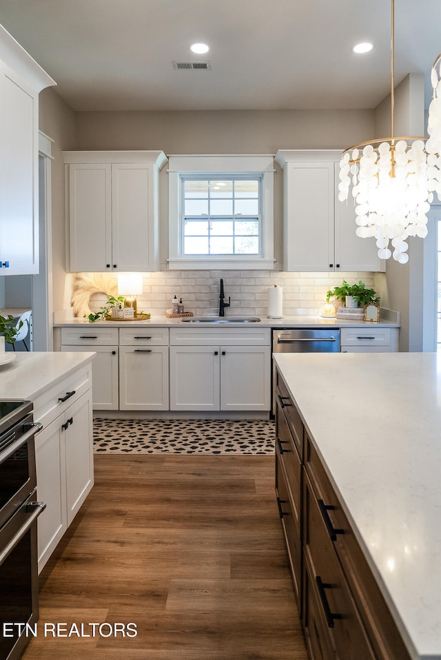 kitchen with light countertops, white cabinets, visible vents, and a sink