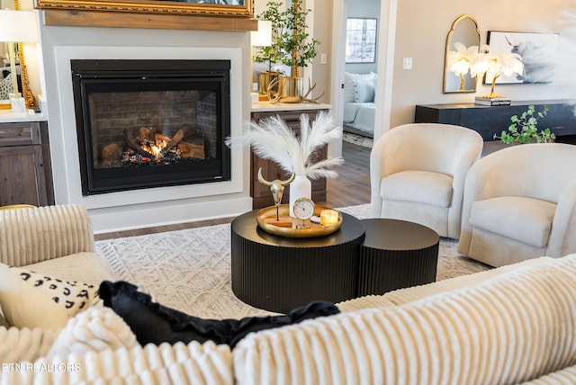 living area with a lit fireplace and wood finished floors