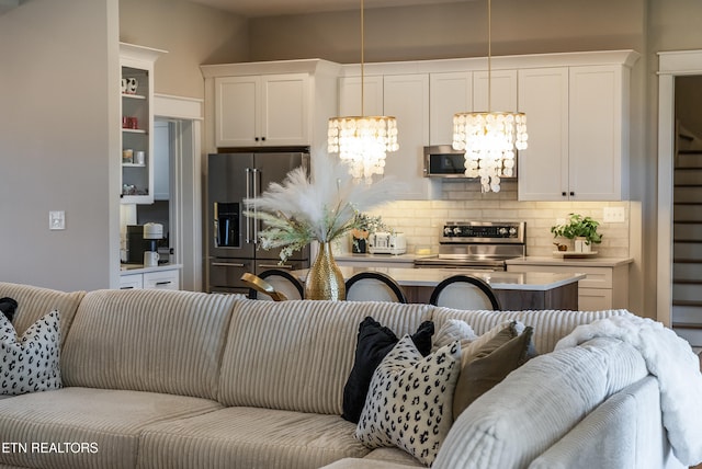 kitchen featuring open floor plan, appliances with stainless steel finishes, white cabinetry, and an inviting chandelier