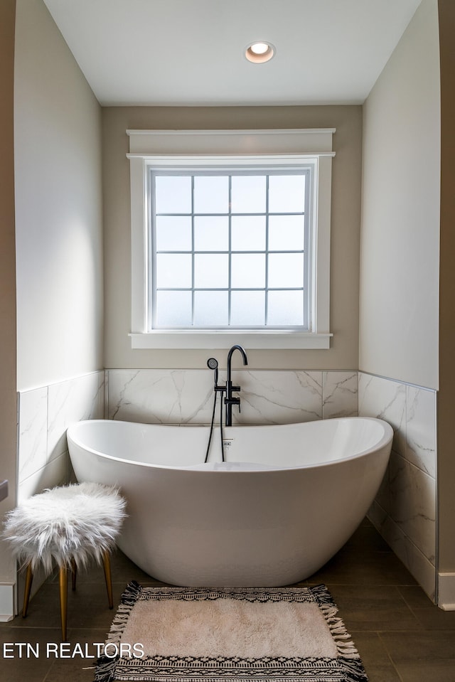 bathroom featuring recessed lighting, a soaking tub, tile walls, and wainscoting