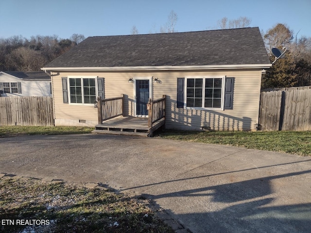 view of front facade featuring a shingled roof, a wooden deck, fence, and crawl space