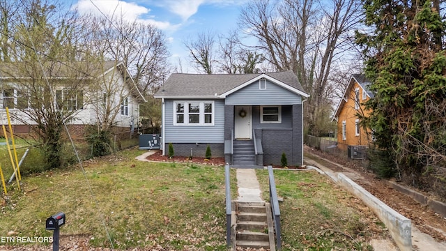 bungalow-style house featuring a front lawn, fence, brick siding, and roof with shingles