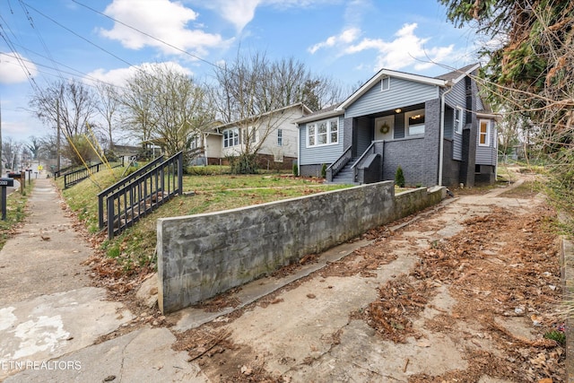 bungalow featuring brick siding and fence