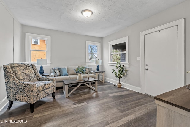 living room with dark wood finished floors, baseboards, and a textured ceiling