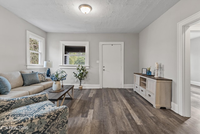 living area with baseboards, a textured ceiling, and dark wood finished floors