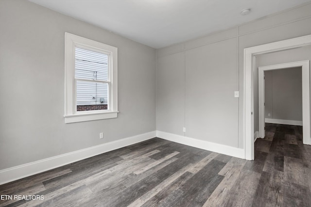 unfurnished room featuring baseboards and dark wood finished floors