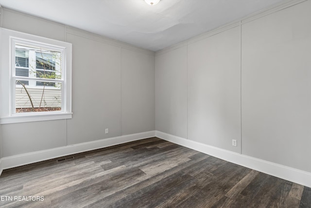 empty room with dark wood finished floors and baseboards