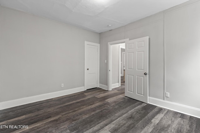 unfurnished bedroom featuring baseboards and dark wood-style flooring