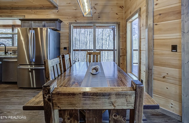 unfurnished dining area with dark wood-style floors, wooden walls, and a sink