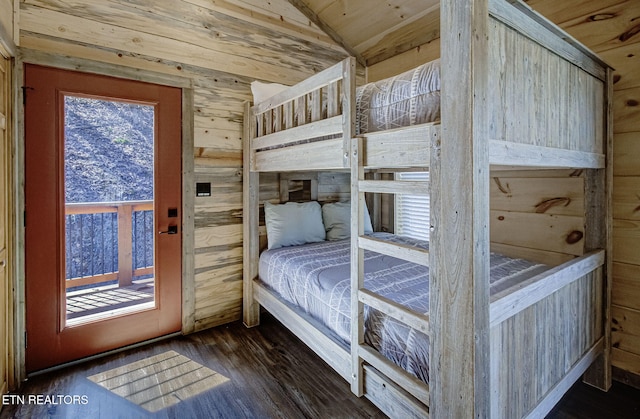 unfurnished bedroom featuring dark wood-type flooring, wooden walls, and lofted ceiling