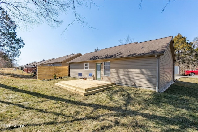 back of house featuring a wooden deck, a lawn, and fence