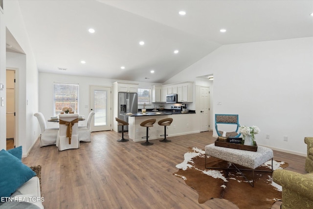 living room featuring visible vents, baseboards, light wood-type flooring, vaulted ceiling, and recessed lighting