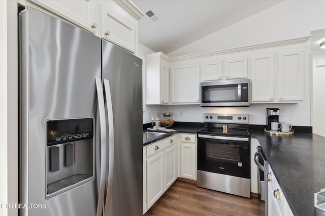 kitchen featuring visible vents, dark wood-type flooring, appliances with stainless steel finishes, white cabinets, and vaulted ceiling