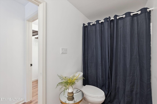 full bathroom featuring toilet, a shower with shower curtain, and wood finished floors