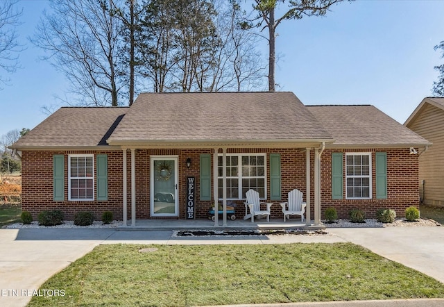 view of front facade featuring brick siding, a shingled roof, and a front lawn