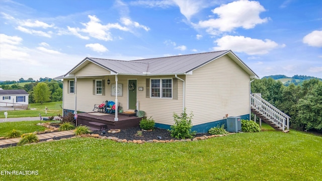 view of front facade featuring central air condition unit, covered porch, a front lawn, and metal roof