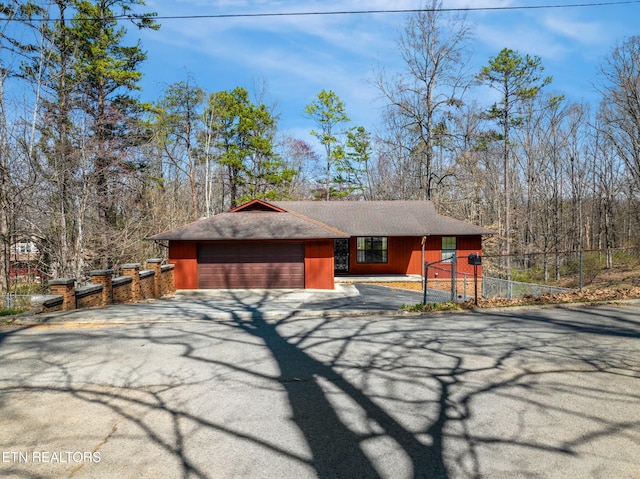 rustic home featuring aphalt driveway, a garage, and fence