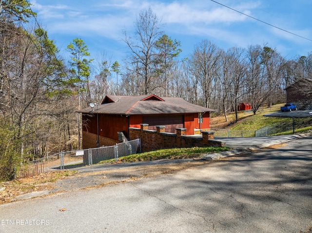 view of side of home with aphalt driveway and a fenced front yard