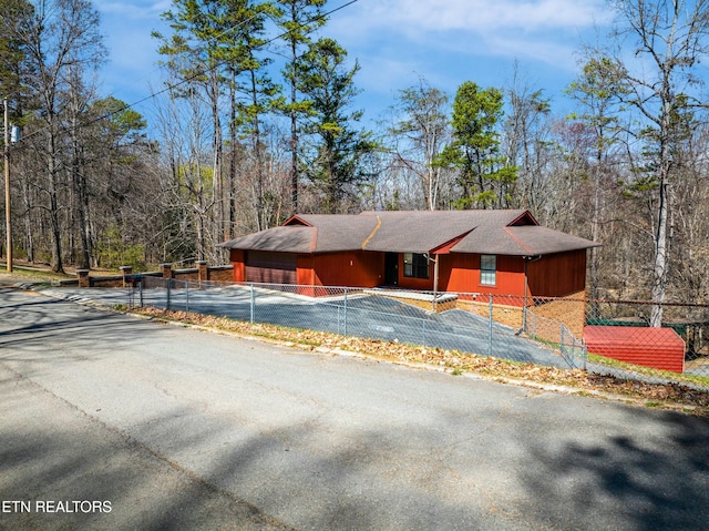 view of front of property featuring a garage, a fenced front yard, and aphalt driveway