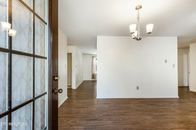 unfurnished room with baseboards, dark wood-style flooring, and a chandelier