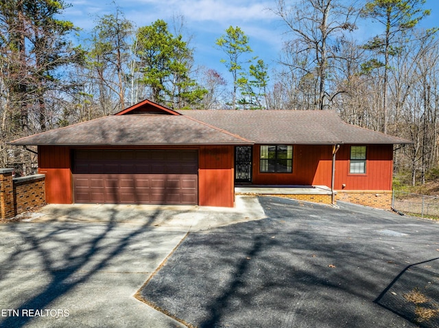 view of front of home featuring an attached garage, driveway, and roof with shingles