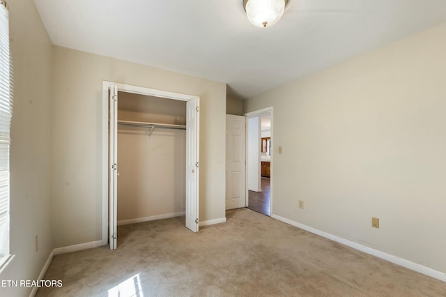 unfurnished bedroom with a closet, carpet floors, and baseboards